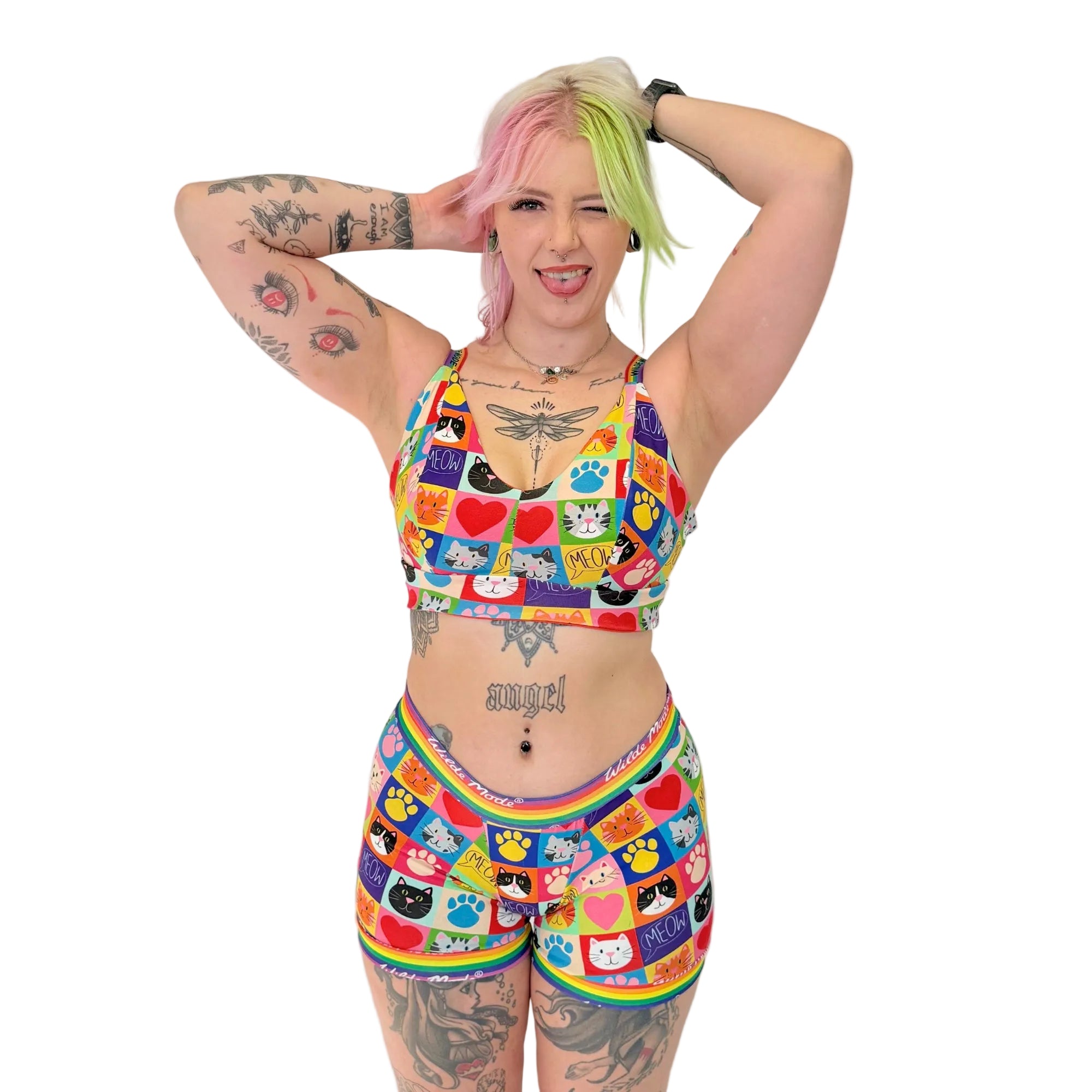 Person wearing a colorful sports bra and shorts set with cat and rainbow patterns on a white background.