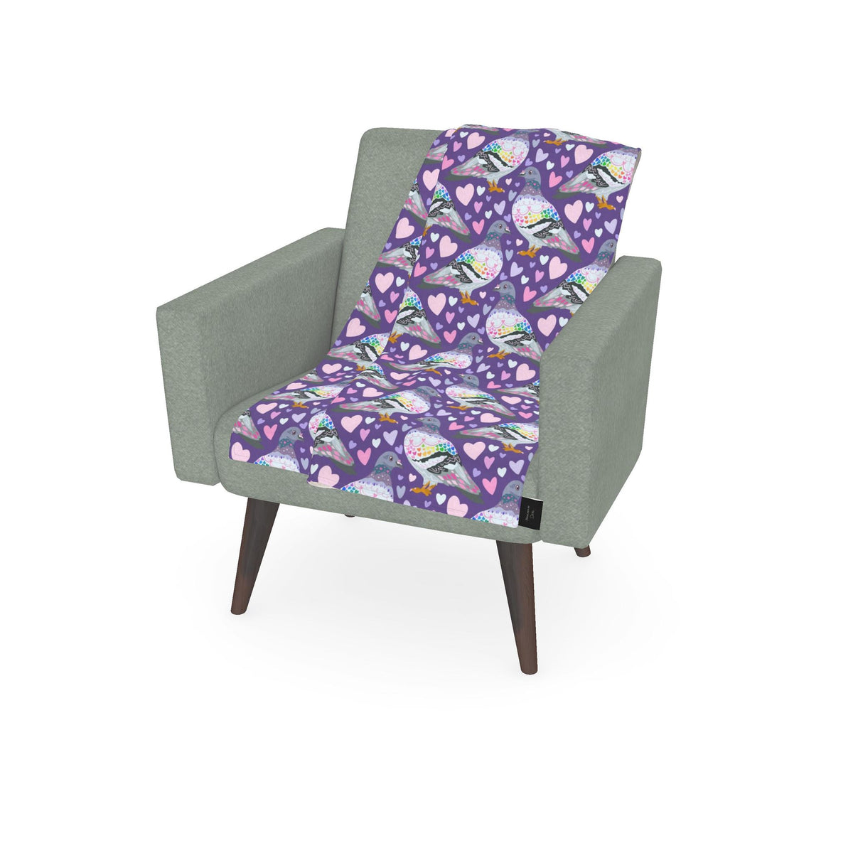 A light sage green armchair with dark wood legs, styled with a purple throw blanket featuring a pattern of butterflies, hearts, and flowers.