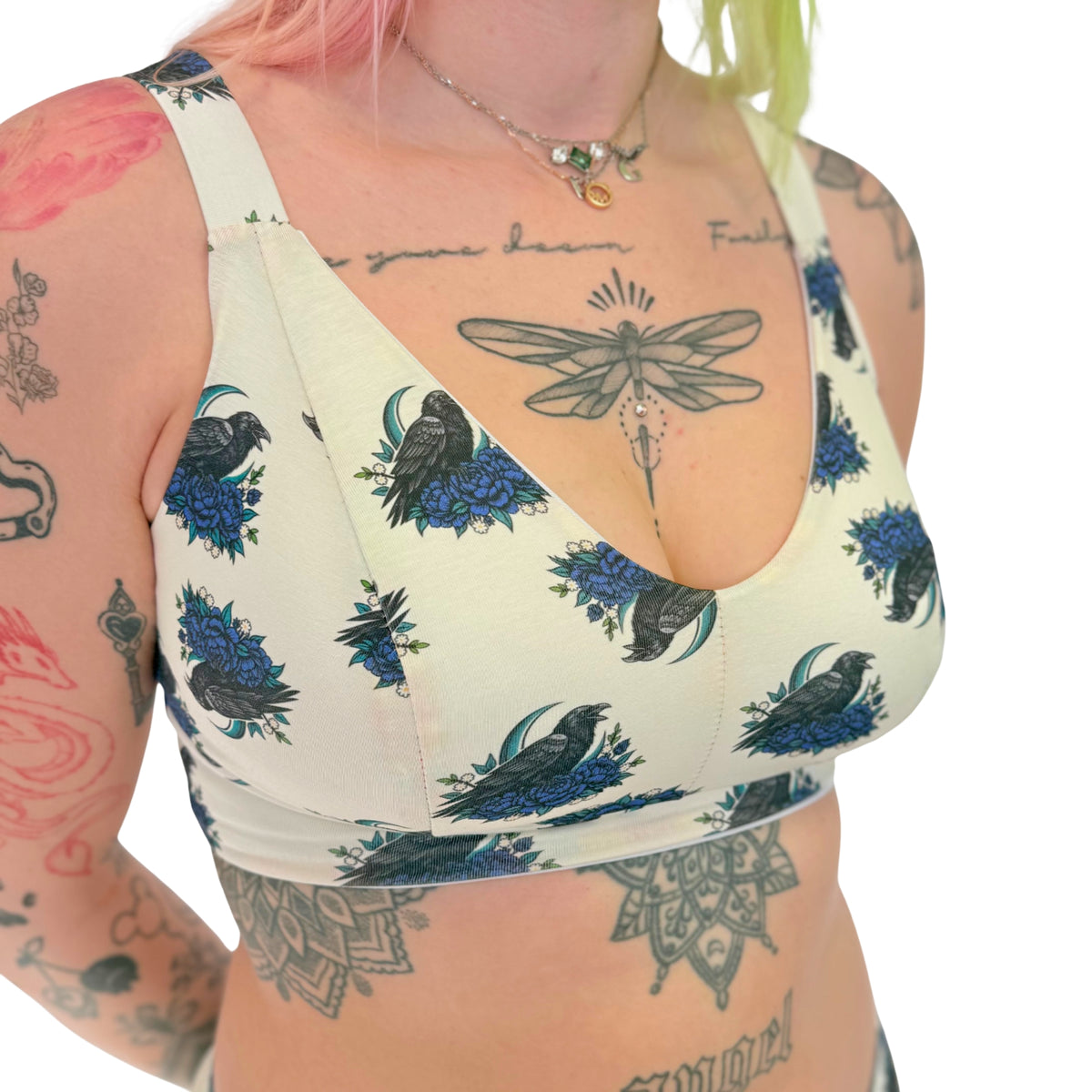 Person wearing a white tank top with black and blue floral and bird pattern on a white background