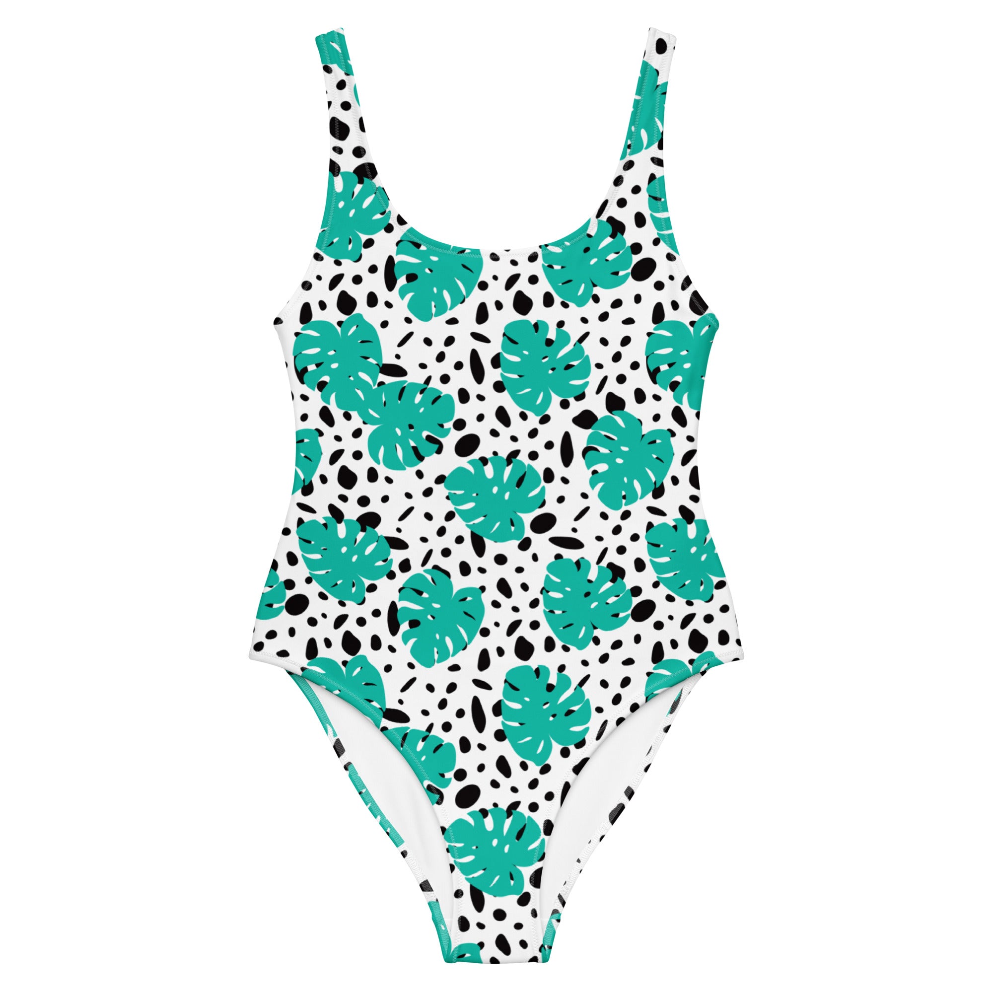 A one-piece swimsuit with a white base, decorated with a pattern of teal monstera leaves and black irregular spots, shown against a plain white background.