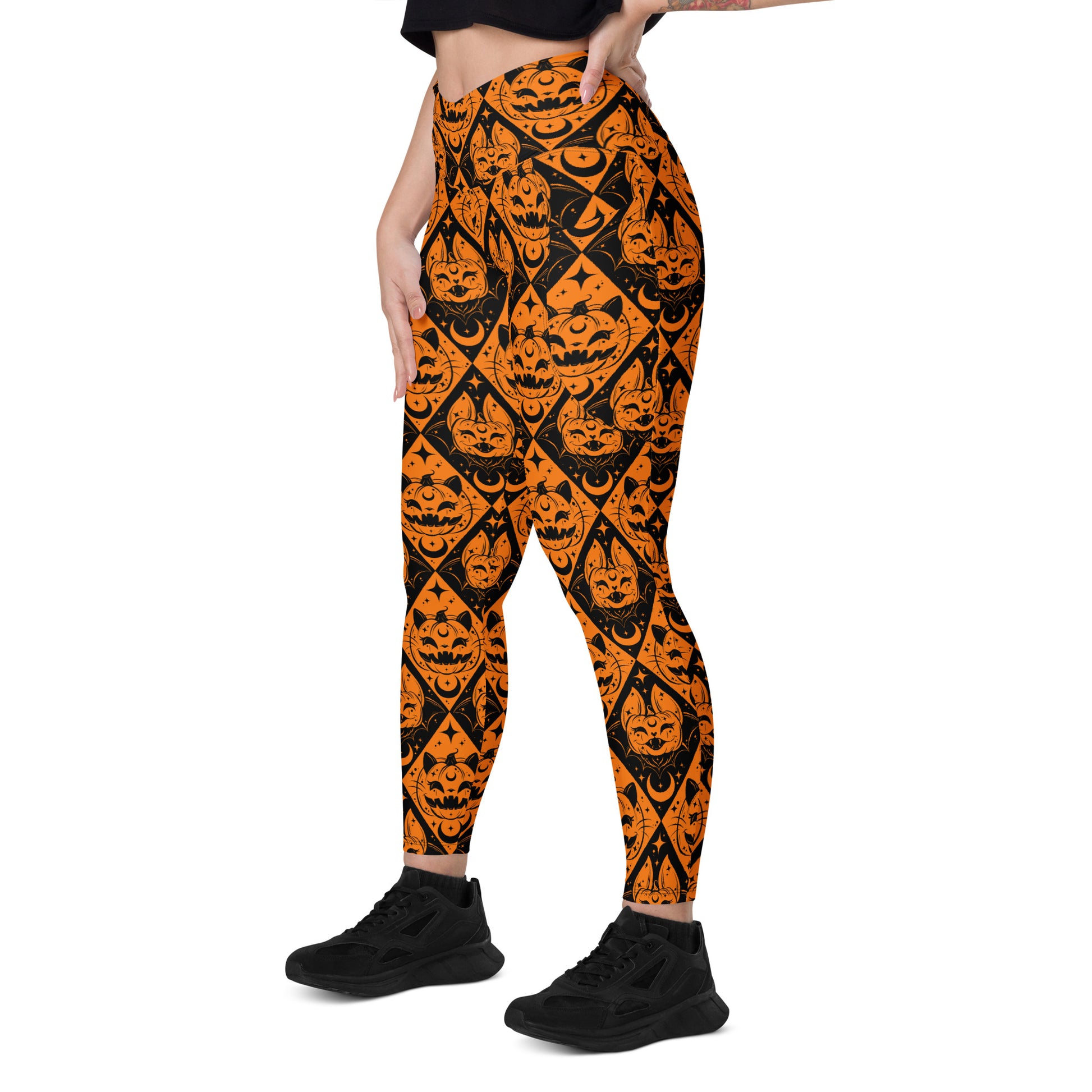 Halloween cat and pumpkin crossover leggings with pockets from Printful, featuring an all-over spooky print on white background.