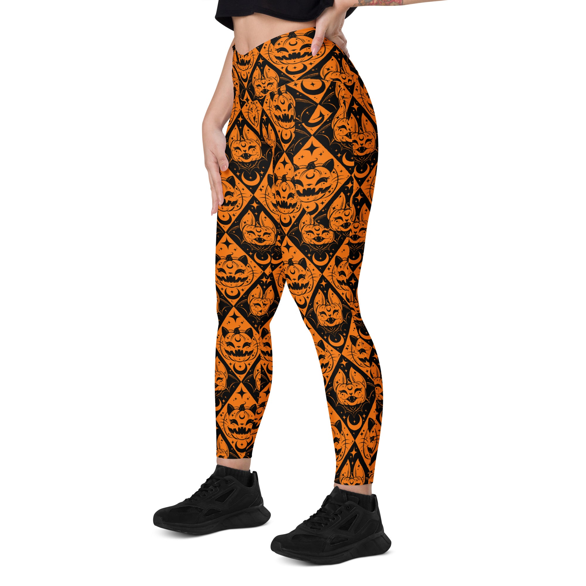 Halloween cat and pumpkin crossover leggings with pockets from Printful, featuring an all-over spooky print on white background.