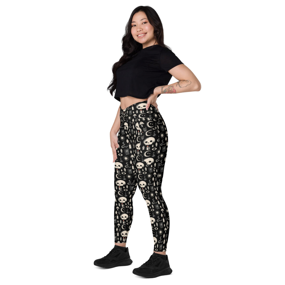 Dark occult crossover leggings with pockets by Printful, featuring an all-over white and black occult print on stretchy fabric.