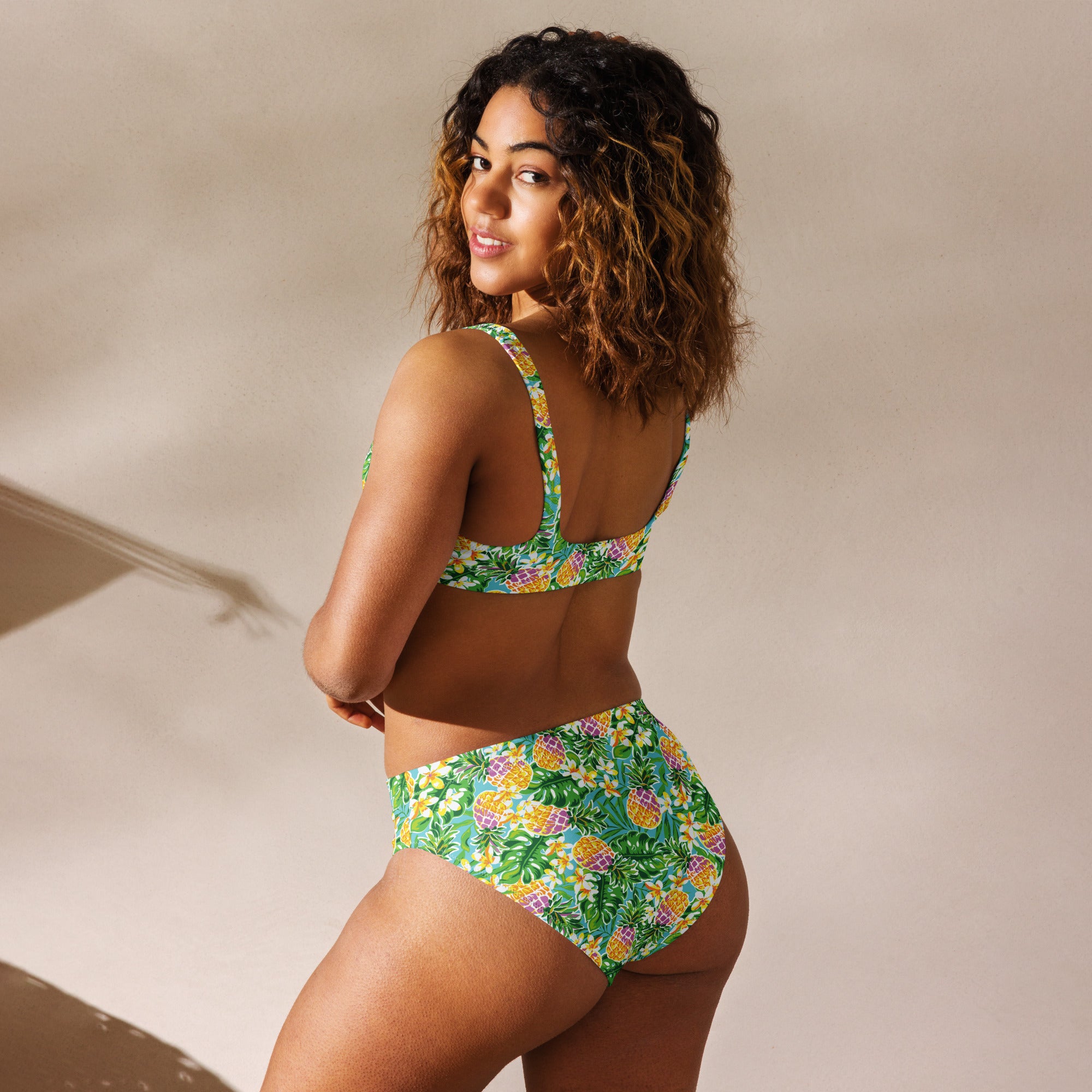 Recycled high-waisted bikini in green with pineapple and flower print, featuring a white back, by Printful.