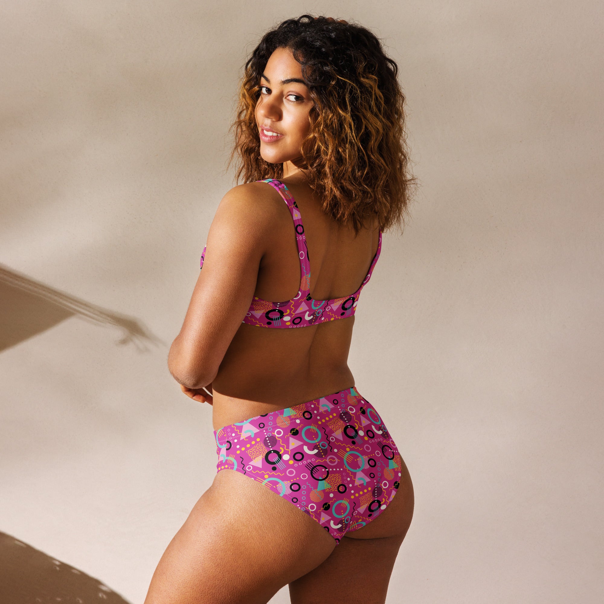 Recycled high-waisted bikini with 90s geometric print in hot pink, shown from the back on a white background.