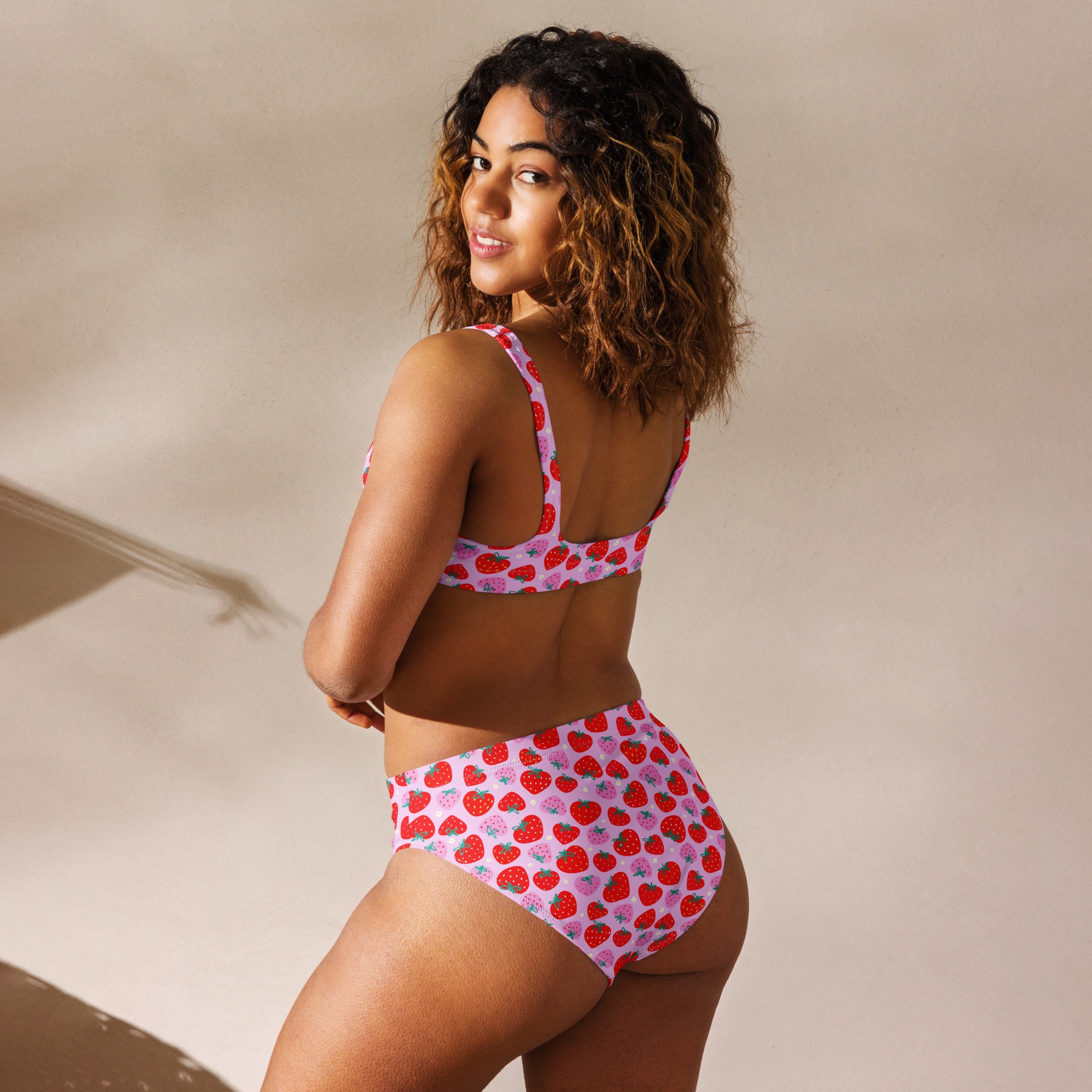 Pink recycled high-waisted bikini with strawberry print from Printful, shown from the back with an all-over floral design.