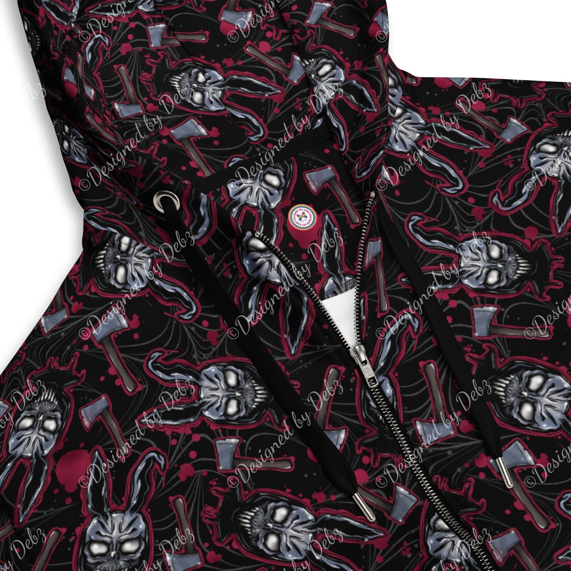 Close-up of a hooded jacket with a black base and an all-over graphic print featuring skulls, axes, and red splatter details. A silver zipper and black drawstrings are visible, with a small circular chest emblem.