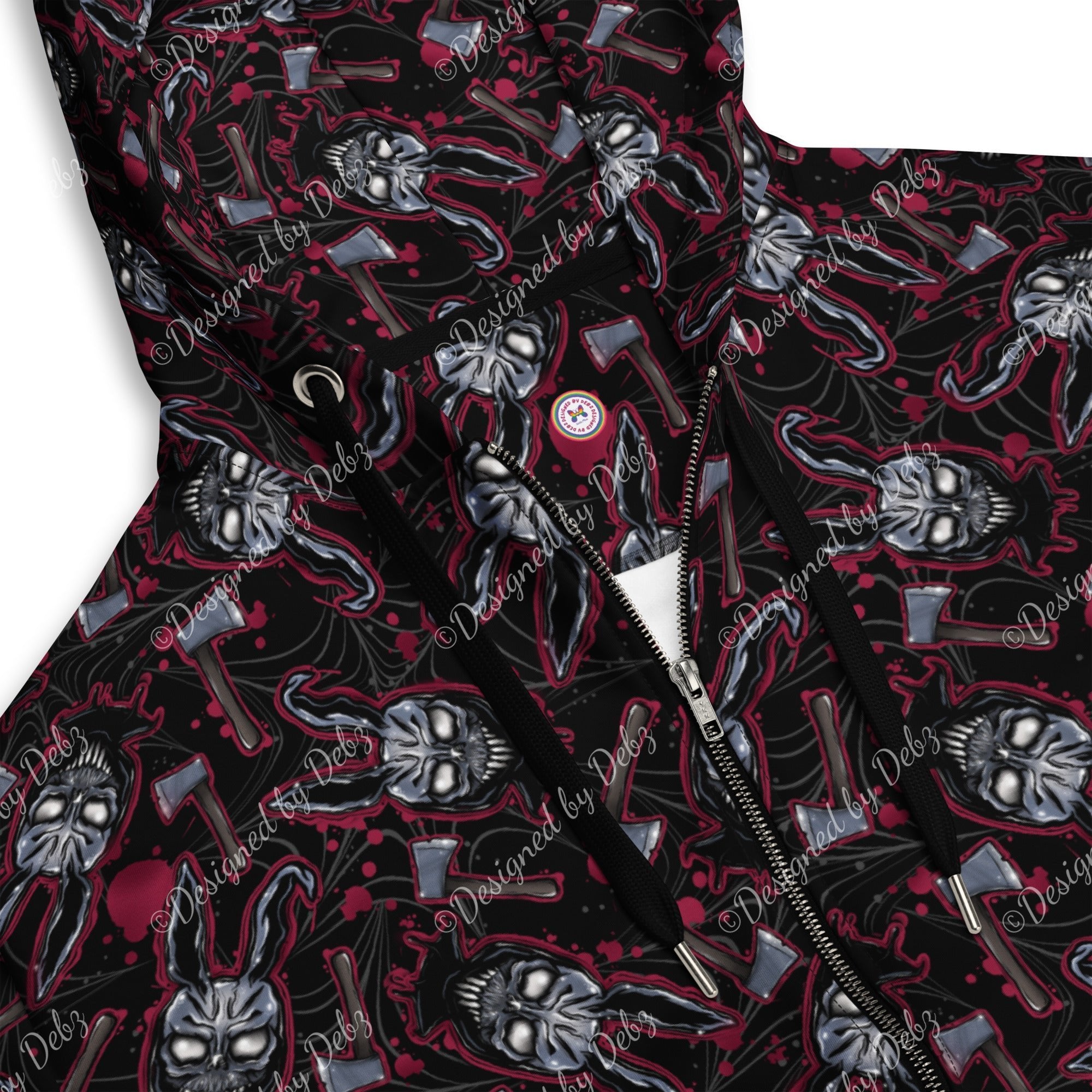 Close-up of a hooded jacket with a black base and an all-over graphic print featuring skulls, axes, and red splatter details. A silver zipper and black drawstrings are visible, with a small circular chest emblem.
