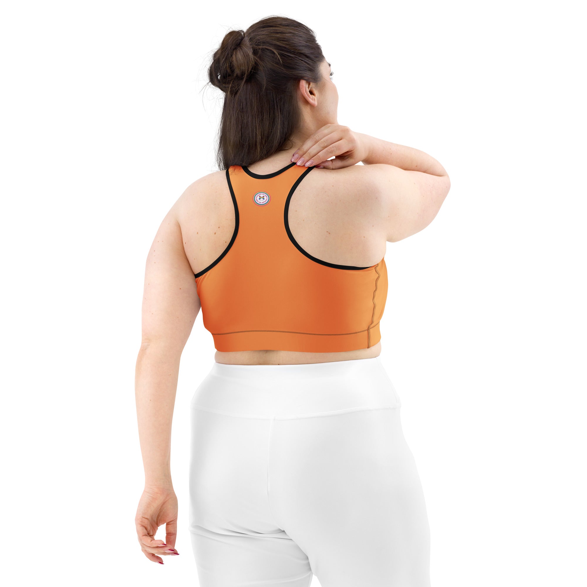 Black all-over-print sports bra by Printful with orange logo and black or white binding, shown from the back.