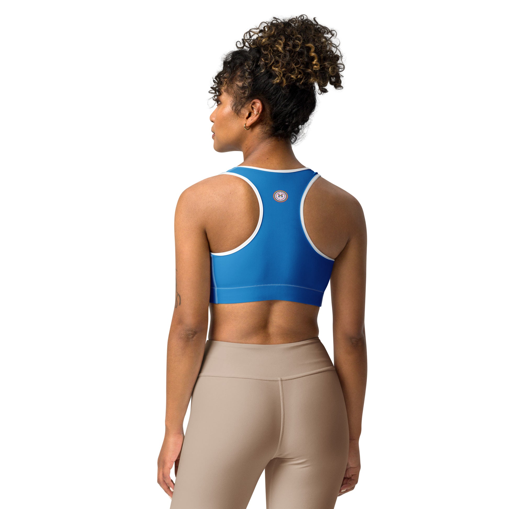 All-over-print white sports bra by Printful with black or white binding, shown from the back, available in XS to 2XL sizes.