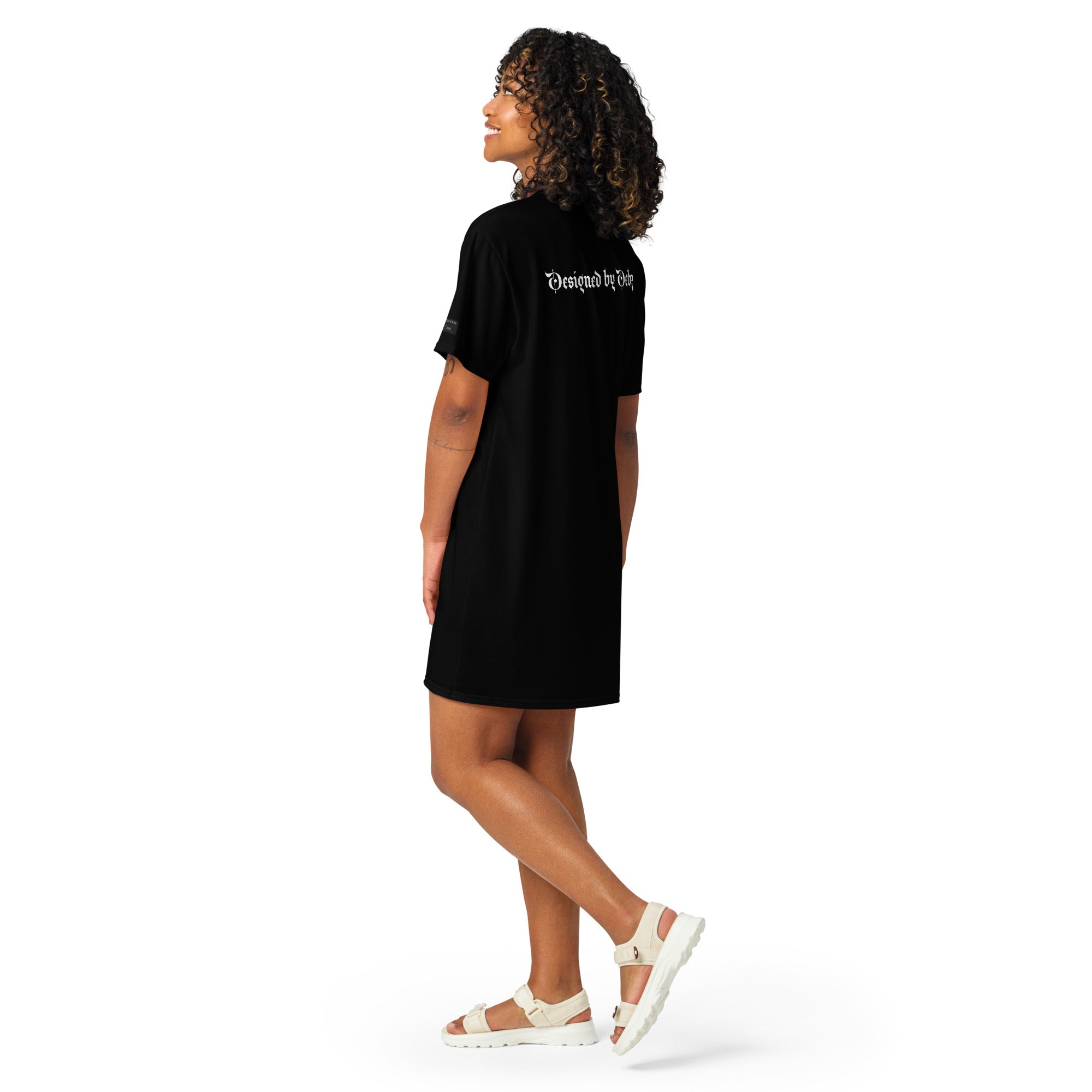 Black Cottage Witch T-Shirt Dress by Printful, showing an all-over white witch-themed print on the back in XS-3XL sizes.