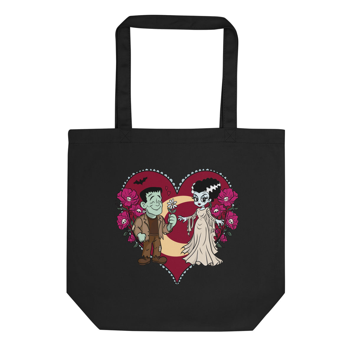 A black canvas tote bag with a cartoon graphic of a vampire and a zombie holding a crescent moon inside a red heart, surrounded by pink flowers, on a plain white background.