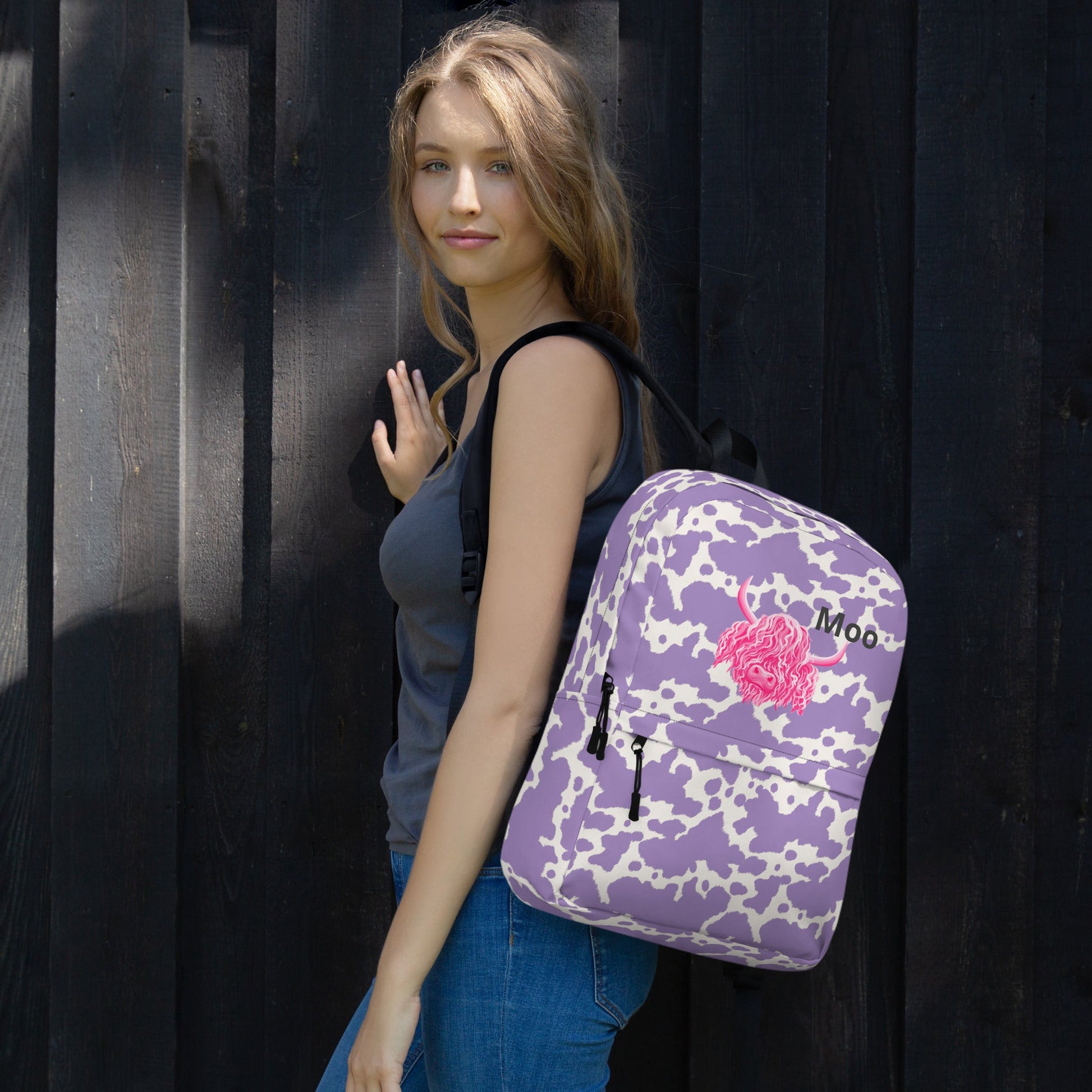 Lilac cow print backpack by Designed By Debz featuring pink cow design, perfect for carrying laptops and everyday essentials.